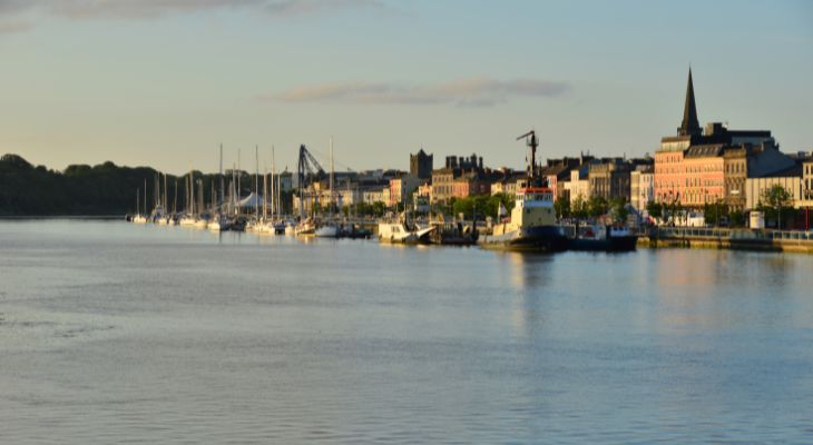 view_of_waterford_ireland_from_the_river_with_multiple_boats_and_the_city_in_the_distance.jpg